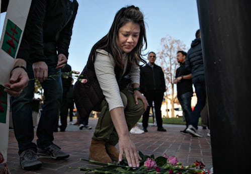 MONTEREY PARK, CA - JANUARY 22: A woman places flowers at a memorial where community members gathere...