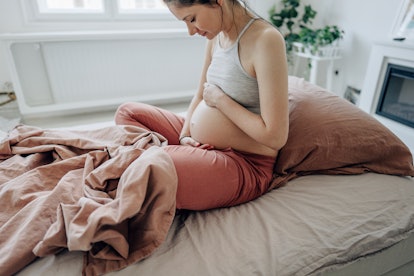 Photo of a young expectant mother stroking her baby bump, in a story about diastasis recti exercises...