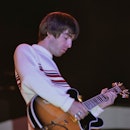 Guitarist and songwriter, Noel Gallagher, performing with British rock group, Oasis, at Knebworth Ho...