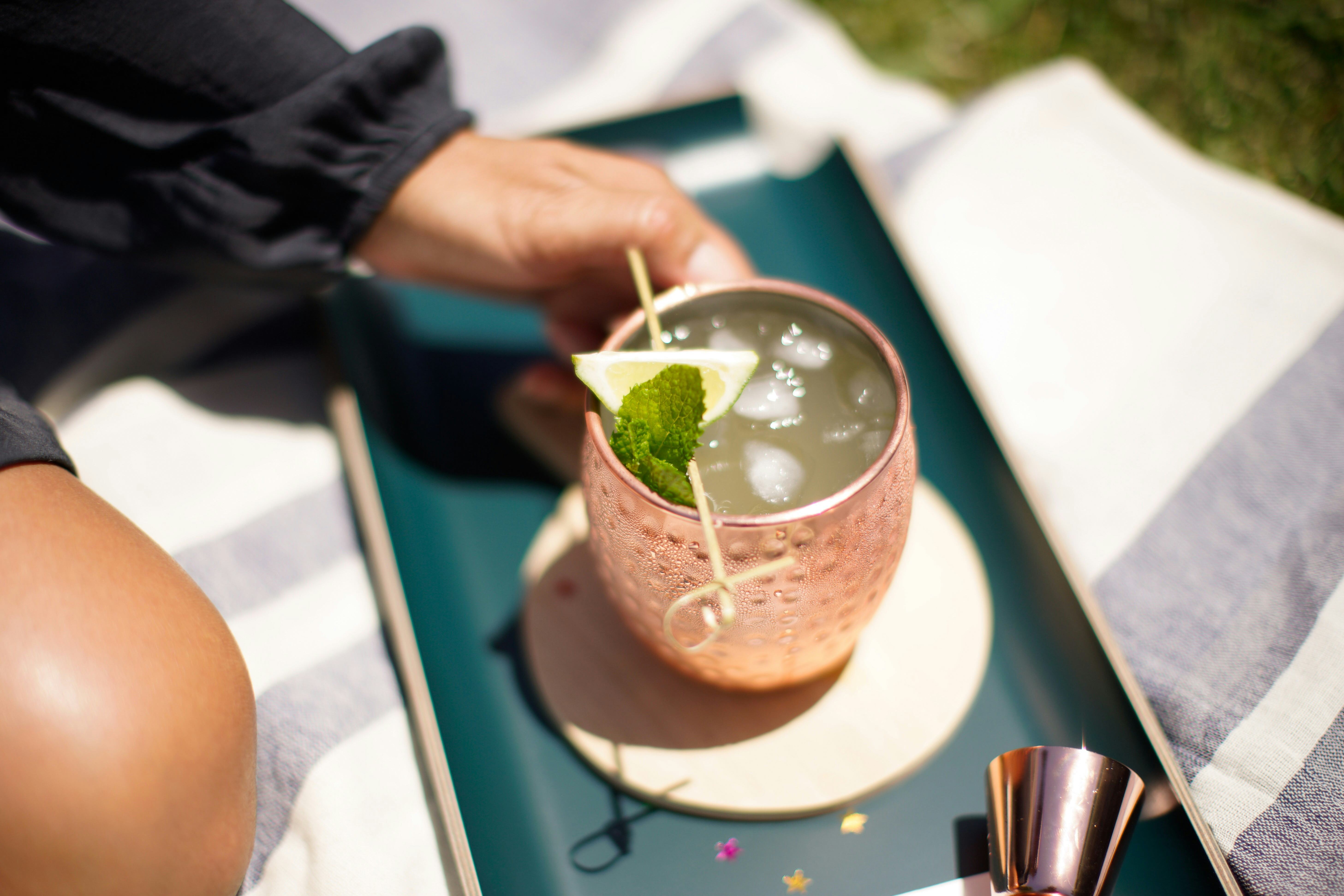 POV of an unidentifiable mature woman outside in the summer sunshine sat on a picnic blanket picking...
