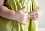 closeup of child holding their stomach in a health article all about stomach pain in kids