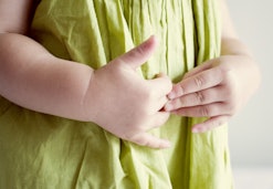 closeup of child holding their stomach in a health article all about stomach pain in kids