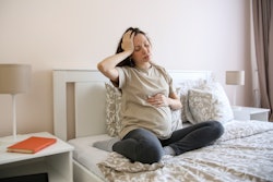 Pregnant woman looking nauseous in article about what foods fight nausea during pregnancy