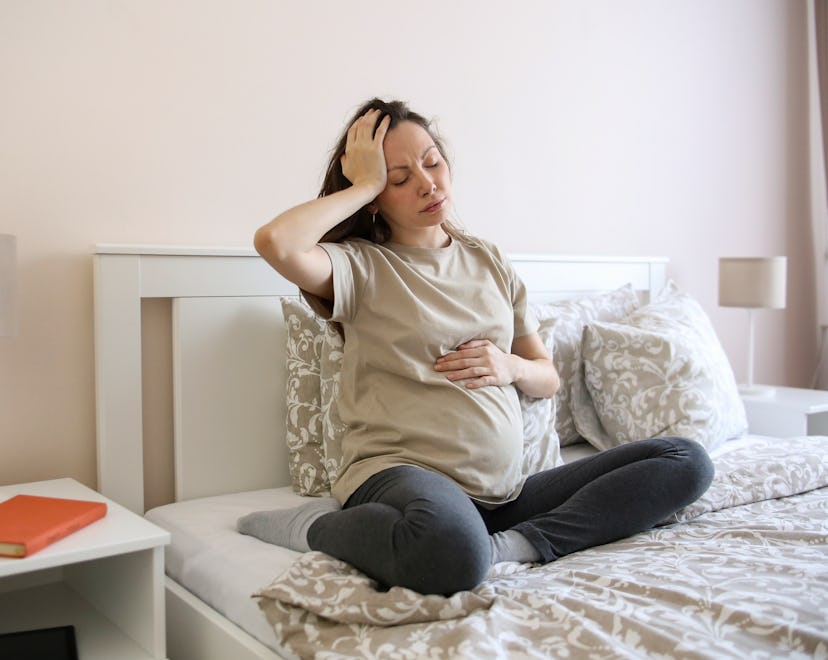 Pregnant woman looking nauseous in article about what foods fight nausea during pregnancy