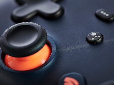 Close-up detail of the Google Assistant button and analogue control stick on a Google Stadia video g...