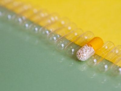 Row of ordered pills - one filled with active drug and the others, empty. Placebo. On green and yell...