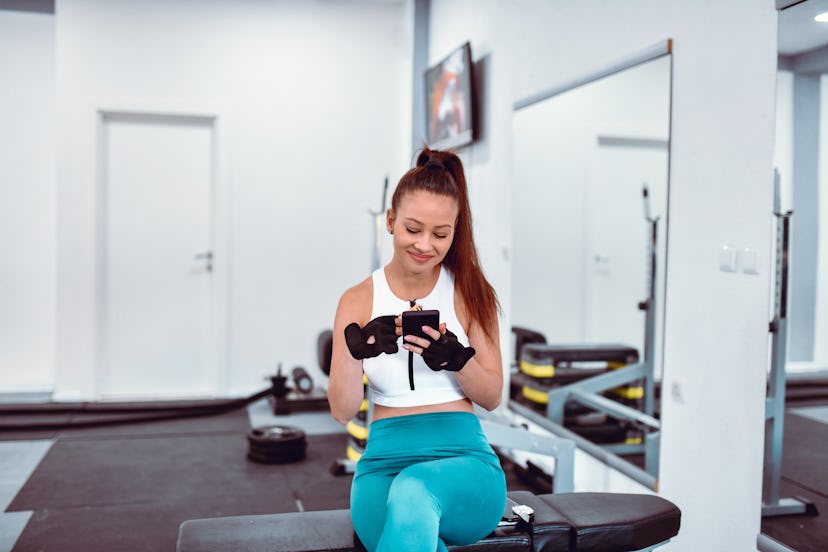 Beautiful Female Athlete Examining Social Media While Eating A Snack After Workout