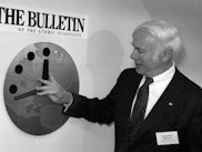 Dr. Leonard Rieser, Chairman of the Board of the Bulletin of the Atomic Scientists, moves the hand o...
