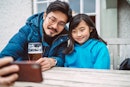 年轻英俊的爸爸和他可爱的女儿在酒吧花园享受啤酒时自拍。