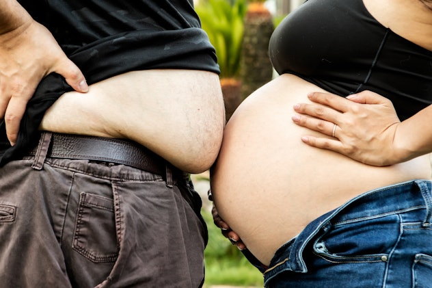 a pregnant person bumping their belly against partner's belly for funny pregnancy announcement 