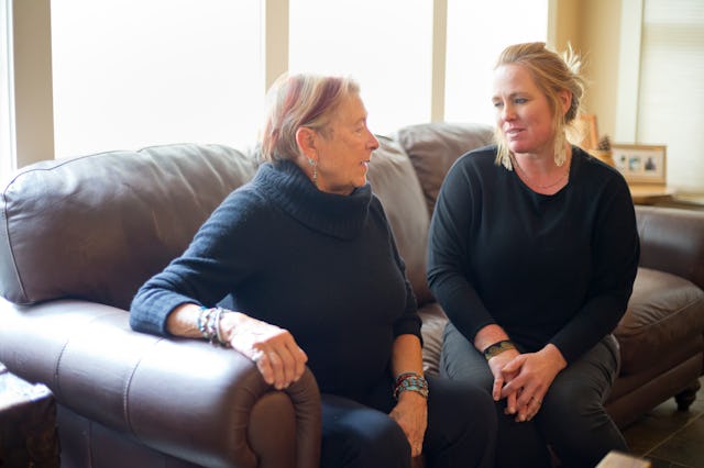 A mother and daughter sit on a sofa in their living room communicating with each other