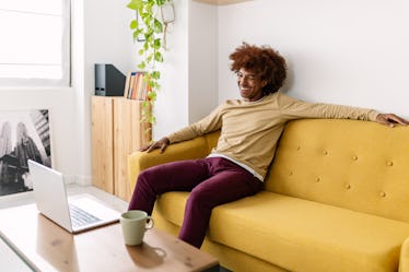 微笑的年轻黑人的美国人周末放松的沙发在笔记本电脑上看电影,休闲行为……