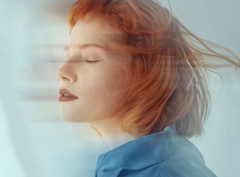 young woman closes her eyes during a long exposure photo as she considers the spiritual meaning of t...