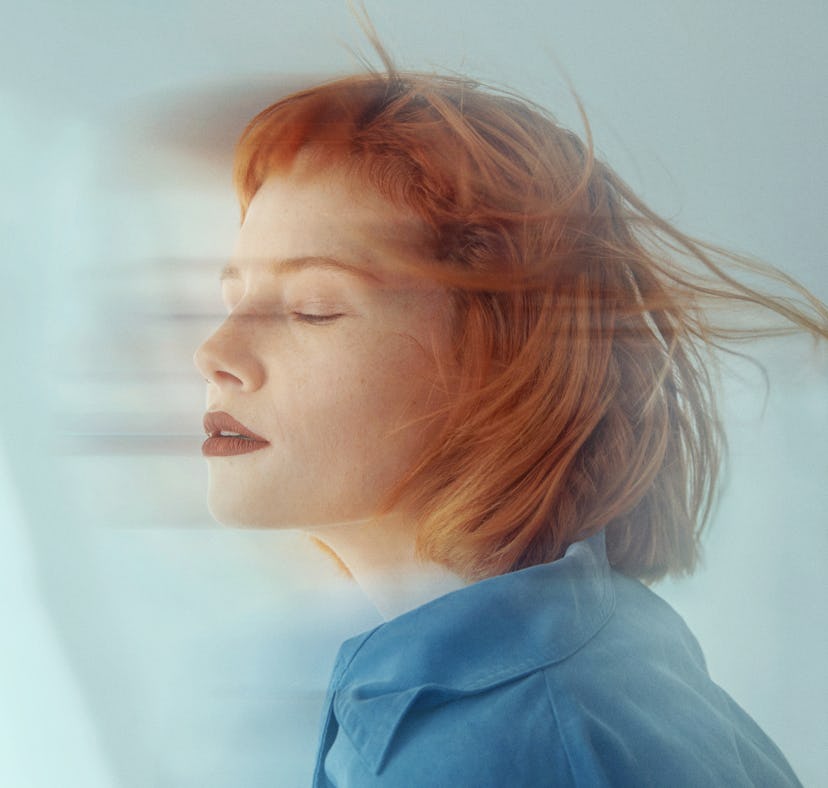 young woman closes her eyes during a long exposure photo as she considers the spiritual meaning of t...