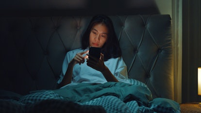 Woman on her phone in bed, possibly searching why her vagina burns after sex