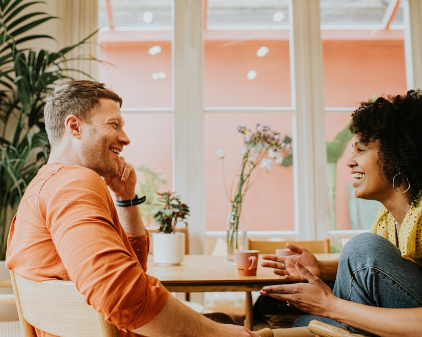 A man and a woman are face-to-face talking, after looking up questions to ask your partner at every ...