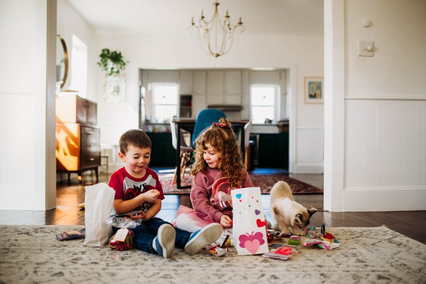 Kids open Valentine's baskets on the floor, in a story about what to write in valentine's day card f...