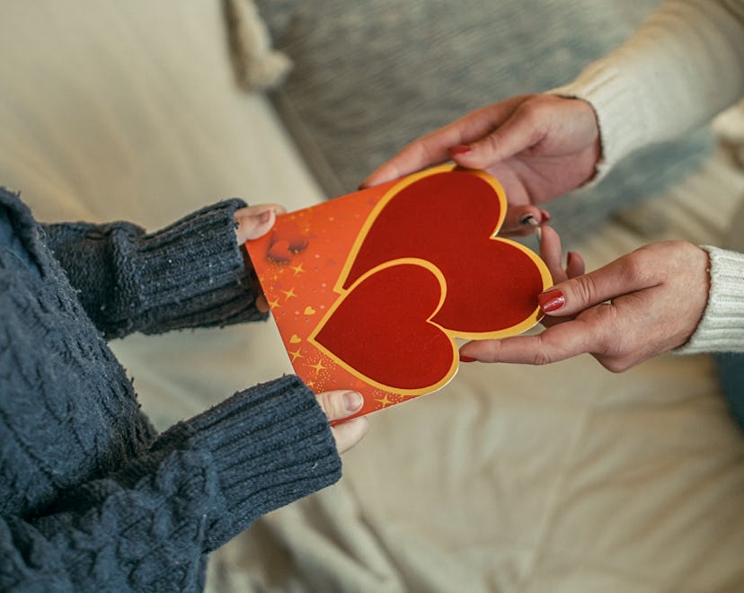 Mother hands child a card, after researching what to write in valentine's day card for child