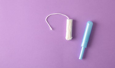 Soft protective and absorbent cotton tampon for women's care on lilac background. Top view. Horizont...