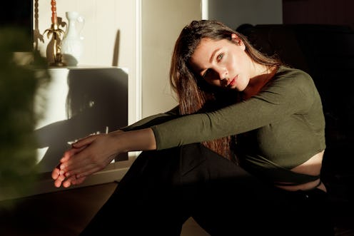 Young attractive woman sitting on the floor while the bright sun is shining on her face.