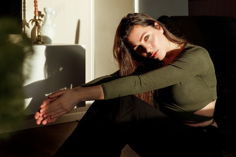 Young attractive woman sitting on the floor while the bright sun is shining on her face.