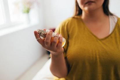 Close up shot of an anonymous plus size woman holding a bottle of perfume.