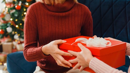 Closeup group of young Asian friends unboxing christmas gifts on sofa in living room at home. Celebr...