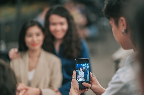 Asian Chinese Lesbian couple portrait photographed with smart phone outdoor dining birthday celebrat...