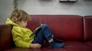 小男孩，大约4岁，坐在沙发上，用平板电脑玩游戏。万博体育app安卓版下载
