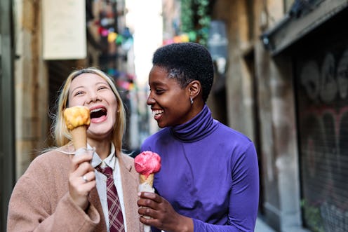Multiethnic friends having fun while eating an ice cream in the street in Barcelona