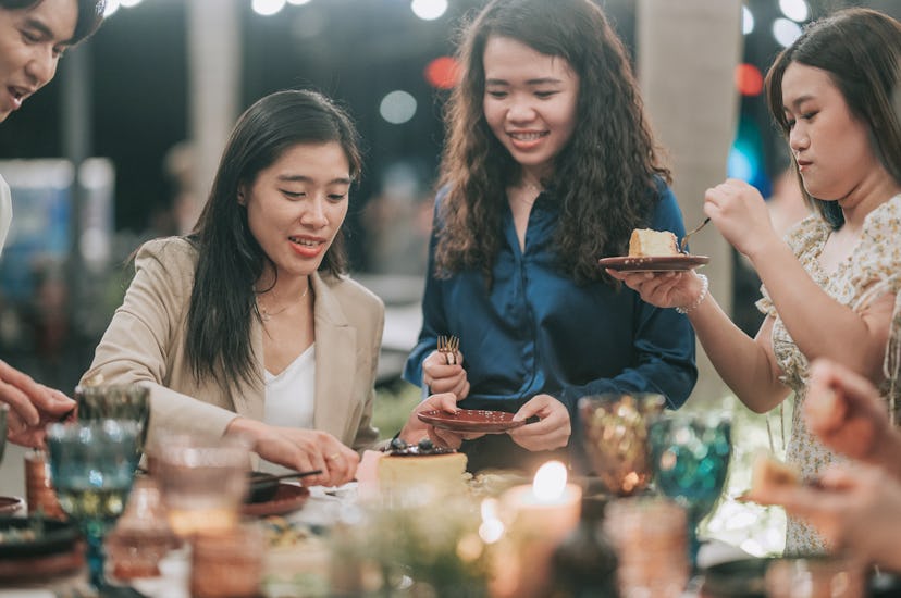 Asian Chinese woman cutting birthday cake with her LGBTQ friends outdoor dining celebration