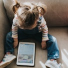 Little girl on a tablet computer in a bright and airy home. Space for copy.