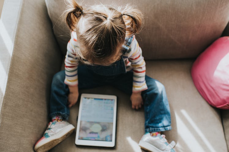 Little girl on a tablet computer in a bright and airy home. Space for copy.