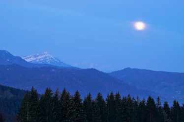 The full moon above a mountain range.