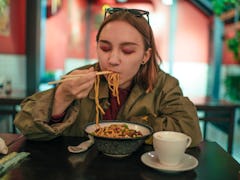 Teenage girl eating ramen recipes from TikTok. 