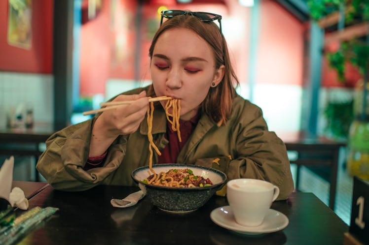 Teenage girl eating ramen recipes from TikTok.