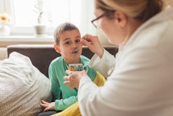 A mom feeds her child soup with a spoon, in a story explaining how sick is too sick to go to school.