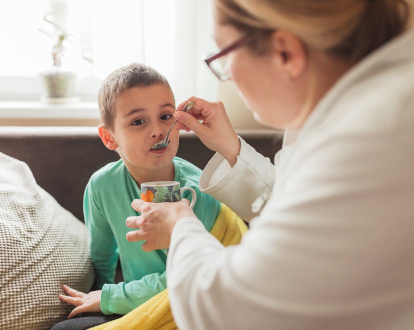 A mom feeds her child soup with a spoon, in a story explaining how sick is too sick to go to school.