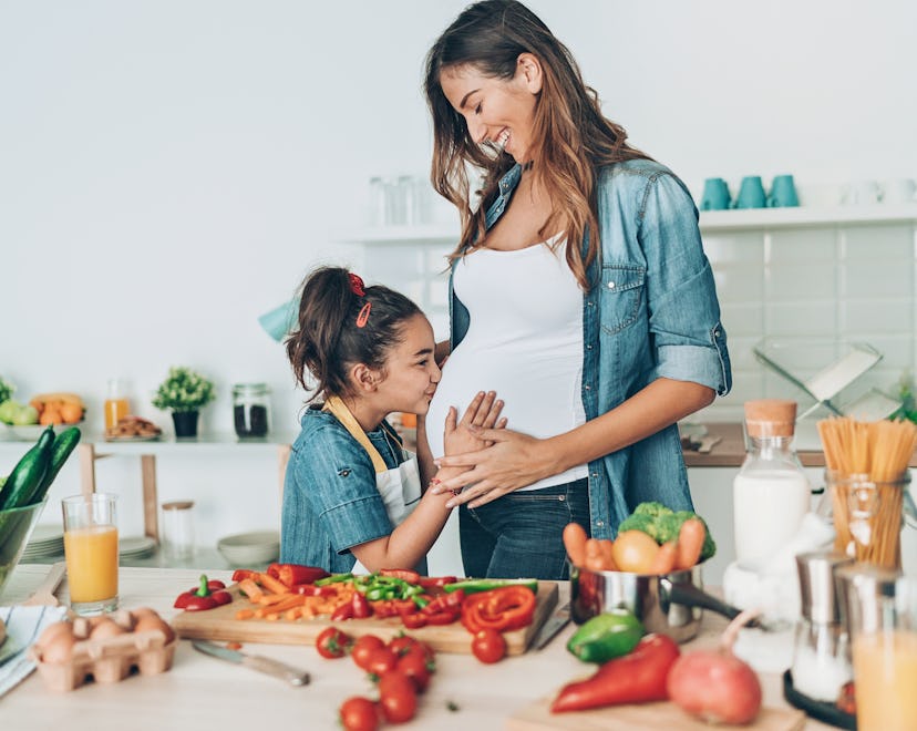 Pregnant young woman and her daughter together in the kitchen can you have spicy food while pregnant...