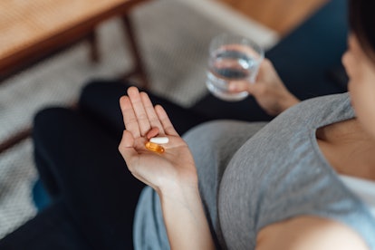Close up of pregnant woman taking vitamin what to do if you forgot prenatal missed prenatal vitamins...