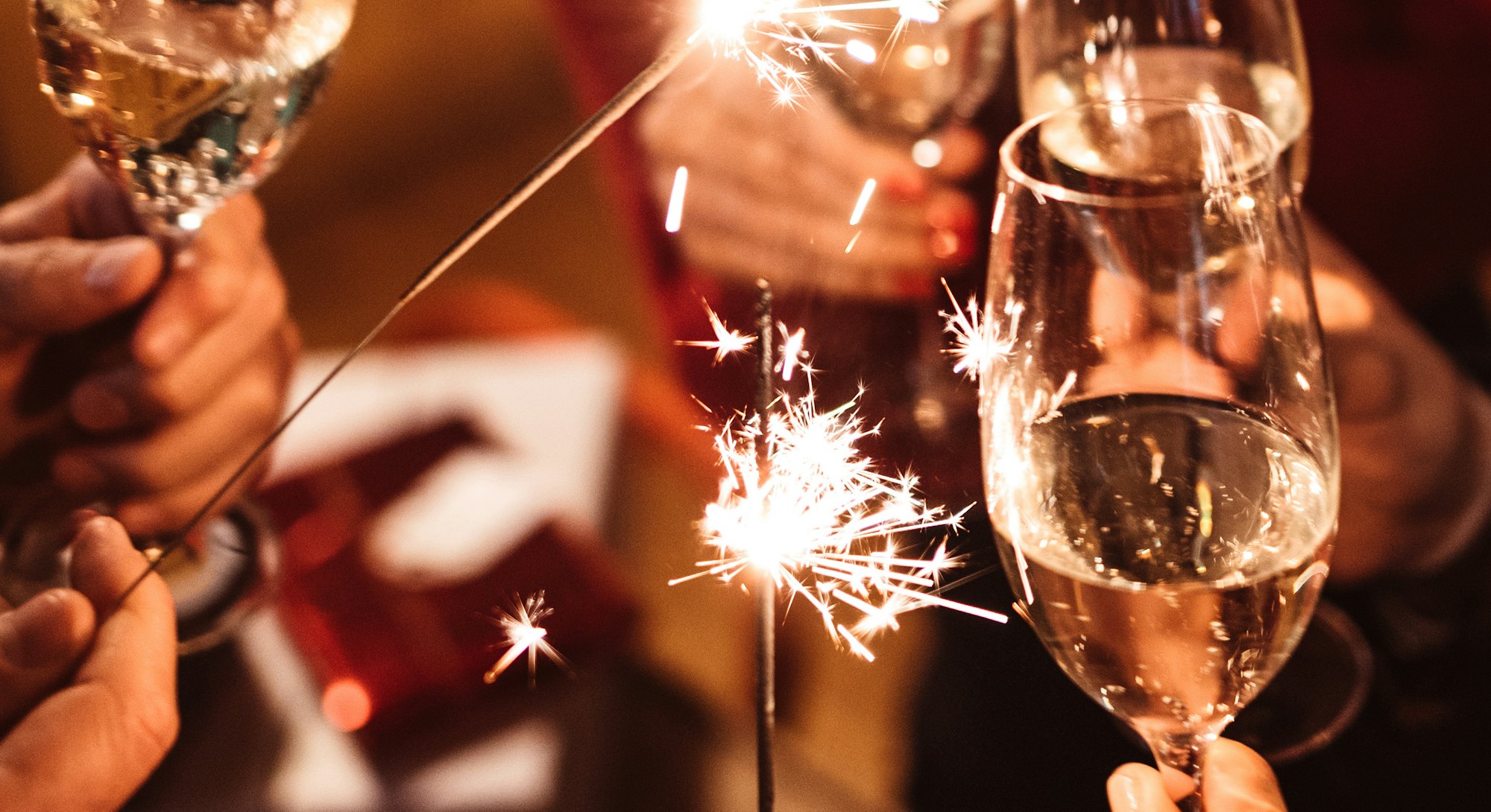 Champagne glasses clinking with sparklers, celebrating how each Zodiac sign makes New Year's resolut...
