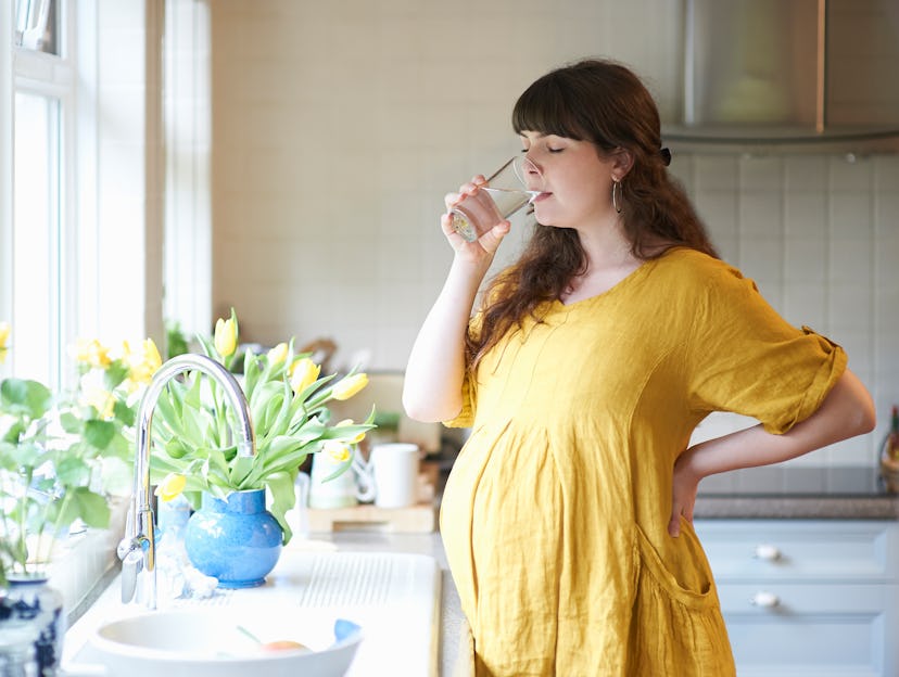 A pregnant woman hydrates in an article about can you dilate without losing your mucus plug.