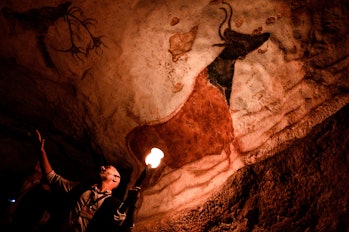 A worker shows paintings inside a life-size replica of Lascaux Cave during a special immersive…