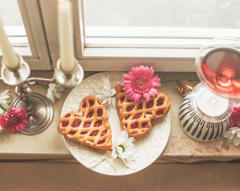 Two hearts cakes and flowers on windowsill in an article on when is valentines day 2023 