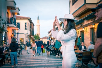 Antalya, Turkey - 12/03/2022: A young female tourist taking photos for social media on the streets o...