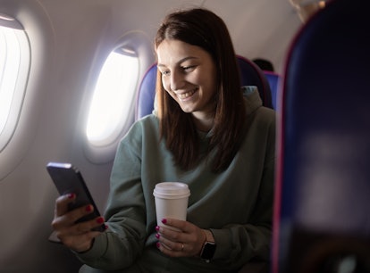 A woman with her phone knows how to get free WiFi on plane with Delta offering free WiFi on all flig...