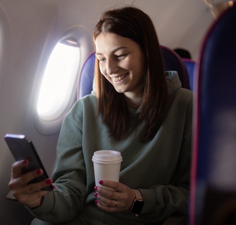 A woman with her phone knows how to get free WiFi on plane with Delta offering free WiFi on all flig...