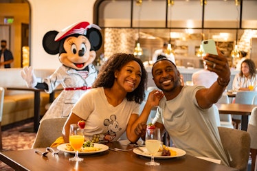 A couple eats at one of the Disney restaurants to use their Disney Dining Promo Card and Walt Disney...