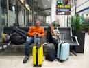父亲和儿子坐在长椅上用手机在等待航班在机场loung……