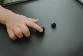 Close up of baby's hand making decision and picking up a bigger sized blueberry on high chair